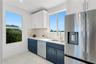 Kitchen featuring two-tone cabinetry, stone-finish countertops, stainless steel appliances, and large windows