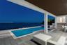 Covered patio with wood-slat ceiling, natural stone tile flooring, swimming pool, built-in spa, and water frontage