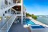 Multi-level exterior featuring a private swimming pool with integrated spa, paved pool deck, metal stair railings, and direct water access with a priv