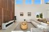 Double-height ceilings with transom windows, full-height vertical wood-slat feature wall, integrated linear fireplace with white floating hearth, and 