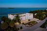 Multi-story waterfront residence featuring a rooftop terrace, elevated construction, multi-car garage, and established landscaping