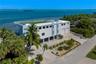 Waterfront residence featuring a rooftop terrace, elevated construction, concrete driveway, and attached two-car garage
