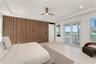 Slatted wood-finish accent wall, tray ceiling with recessed lighting, light-toned wood-finish flooring, and glass French doors leading to an exterior 