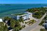 Waterfront multi-story residence featuring a rooftop terrace with synthetic turf, perimeter railing, paved driveway, and attached two-car garage