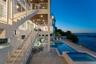 Multi-level exterior featuring white cable-railing staircases, a covered patio with recessed lighting, an in-ground swimming pool, and an attached spa