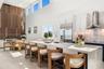Kitchen featuring a waterfall island with stone countertop, cabinetry with integrated appliances, vertical wood-paneling wall feature, soaring ceiling