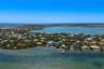 Aerial perspective of coastal property featuring direct water frontage, a private deep-water dock, and tropical vegetation within a waterfront setting