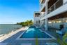 Waterfront exterior featuring a multi-level structure with recessed balconies, horizontal cable railings, a rectangular swimming pool with an integrat