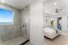 Walk-in shower featuring large-format tile surround, integrated window, handheld showerhead, pebble-finish flooring, and a frameless glass partition