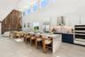 Open-concept kitchen featuring double-height ceilings, a large stone-topped waterfall island, custom two-toned cabinetry, built-in stainless steel app