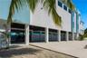 Modern multi-level exterior featuring white stucco finish, covered parking area, concrete driveway, horizontal slat privacy fencing, and recessed ligh
