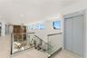 Open landing featuring large-format tile flooring, a glass-panel railing with a wood-finish handrail, a private elevator, recessed ceiling lighting, a