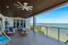 Covered terrace featuring a slatted wood-paneled ceiling, recessed lighting, ceiling fans, large-format tile flooring, and a metal railing system