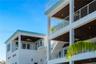 Multi-level exterior featuring stacked covered balconies, white horizontal railings, recessed lighting, and dark-toned plank ceilings