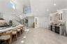 Open-concept kitchen featuring a large central island with waterfall-edge countertop, natural stone-style backsplash, integrated wine refrigeration, b