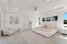Spacious interior featuring a tray ceiling, recessed lighting, neutral large-format tile flooring, and a modern ceiling fan