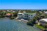 Waterfront multi-story residence featuring a private pool, multiple tiered balconies, a rooftop terrace, and stone shoreline stabilization