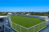 Rooftop terrace featuring artificial turf flooring, white metal railings, and perimeter wall lighting