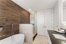 Bathroom featuring a textured wood-slat feature wall, freestanding soaking tub, walk-in glass-enclosed shower, dark countertop with an integrated basi