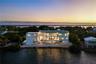 Waterfront residence featuring multi-level balconies, an in-ground swimming pool, a rock-lined shoreline, and a rooftop terrace