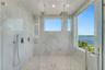 Walk-in shower featuring floor-to-ceiling stone-patterned tile, dual ceiling-mounted rainfall showerheads, a handheld sprayer, a glass enclosure, and 