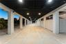 Covered parking area featuring concrete pavers, white lattice privacy screens, structural support columns, and recessed ceiling lighting