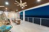 Covered terrace featuring a slatted wood-finish ceiling, recessed lighting, ceiling fans, large-format tile flooring, and a white horizontal rail syst