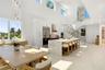 Open-concept kitchen featuring an expansive stone-topped waterfall island, custom white cabinetry, stainless steel professional-grade appliances, floa