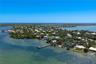 Aerial perspective of waterfront property featuring an extended deep-water dock, direct shoreline access, and expansive coastal surroundings