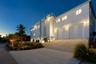 Contemporary multi-level exterior featuring a stucco facade, double-bay roll-up garage, concrete driveway, and elevated architectural detailing