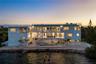 Waterfront multi-story residence featuring a private swimming pool, expansive stacked balconies with metal railings, a rooftop terrace, and a stone-li