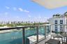 Covered balcony featuring a glass panel railing, tiled flooring, and expansive water and urban scenery