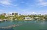 Waterfront estate featuring a paved pool deck, private dock, two-story structure with extensive glass glazing, and mature perimeter landscaping