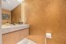 Textured wall finish, floating vanity with wood-grain cabinetry, stone countertop, integrated vertical lighting, and recessed ceiling lighting
