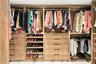 Custom closet organization system featuring wood-finish cabinetry, multi-tiered hanging rods, integrated shelving for footwear, and deep drawers with 