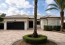 Exterior featuring a white stucco facade, a multi-car garage with black doors, a tile roof, decorative wall medallions, and a paved circular driveway