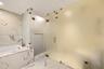 Soaking tub with a wall-mounted faucet, large-format stone-patterned tile flooring and wall cladding, and frosted glass partition walls with integrate