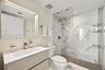 Floating vanity featuring a rectangular integrated sink, quartz countertop, and gold-tone faucet, complemented by a large framed vanity mirror, glass-