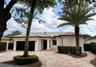 Stucco exterior featuring a tiled hip roof, custom masonry paver driveway, two-car garage with black doors, and ornamental wall medallions