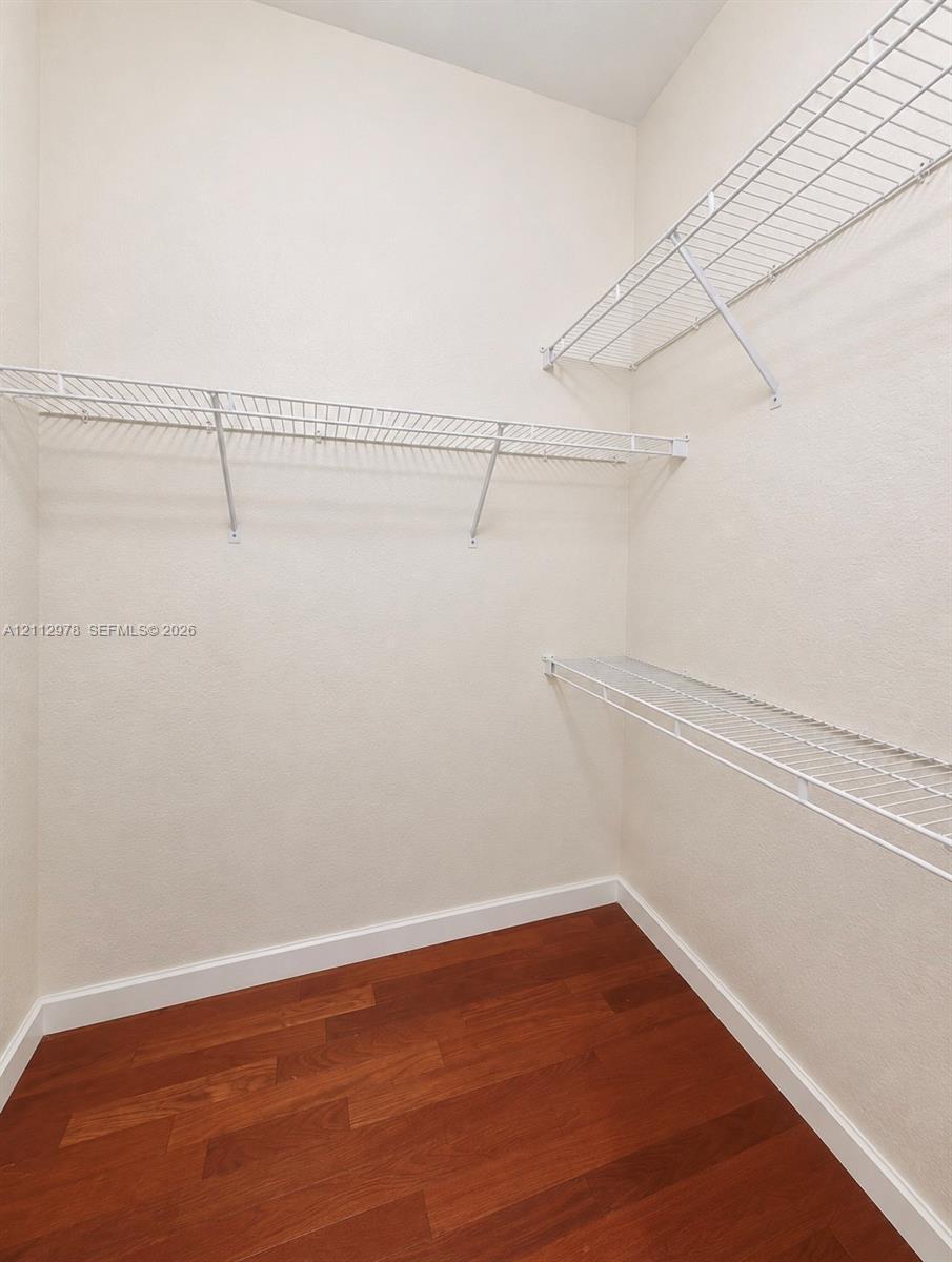 Storage area featuring wood-finish flooring and tiered white wire shelving