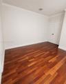 Room featuring wood-finish flooring, neutral wall paint, crown molding, and double-panel doors with matte black hardware