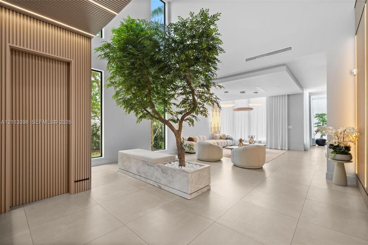 Open-concept interior featuring vertical wood-slat wall paneling, floor-to-ceiling windows, large-format tile flooring, and a built-in stone planter