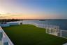 Expansive rooftop terrace featuring synthetic turf flooring and horizontal cable railing