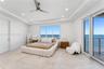 Tray ceiling with recessed lighting, large-format tile flooring, ceiling fan, and floor-to-ceiling glass sliding doors opening to an exterior balcony