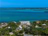 Waterfront property featuring direct coastal access, multi-level structural design, white exterior cladding, and expansive surrounding tropical vegeta