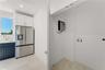 Stainless steel french-door refrigerator, dark navy cabinetry, white upper cabinetry, recessed lighting, and designated utility area with plumbing hoo