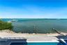 Waterfront property featuring a private swimming pool, stone-paver patio, rock-lined seawall, and a private dock