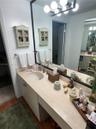 Bathroom vanity featuring a solid-surface countertop, an integrated oval sink, a brushed metal faucet, a full-width mirror with a black frame, and a m