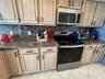 Kitchen featuring natural-finish wood cabinetry, stone countertops, coordinating stone backsplash, and stainless steel appliances