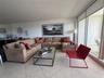 Living area featuring expansive floor-to-ceiling glass doors, neutral tile flooring, and a full-length wall mirror